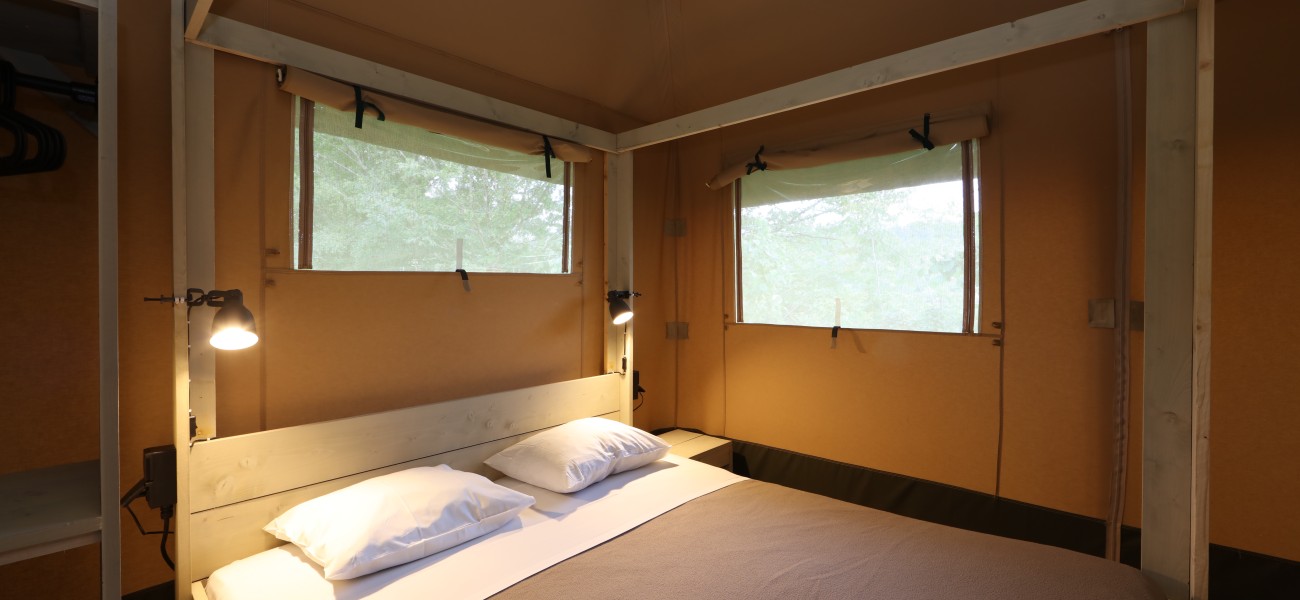 Chambre principale lumineuse dans l'écolodge VIP au Camping Lac de Carouge.